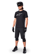 Ciclista de montaña con el Jersey de manga corta Alpinestars A-Dura Dri Oscar en Negro Reflectante, con un gran logotipo blanco en el pecho, combinado con pantalones cortos de MTB, guantes y casco negros a juego, ropa técnica de ciclismo para rendimiento off-road