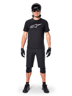 Jersey de manga corta Alpinestars A-Dura Dri Oscar, negro reflectante, combinado con pantalones cortos de MTB, guantes, rodilleras y casco negros a juego, con un gran logotipo de Alpinestars blanco en el pecho, equipamiento completo de ciclismo de montaña