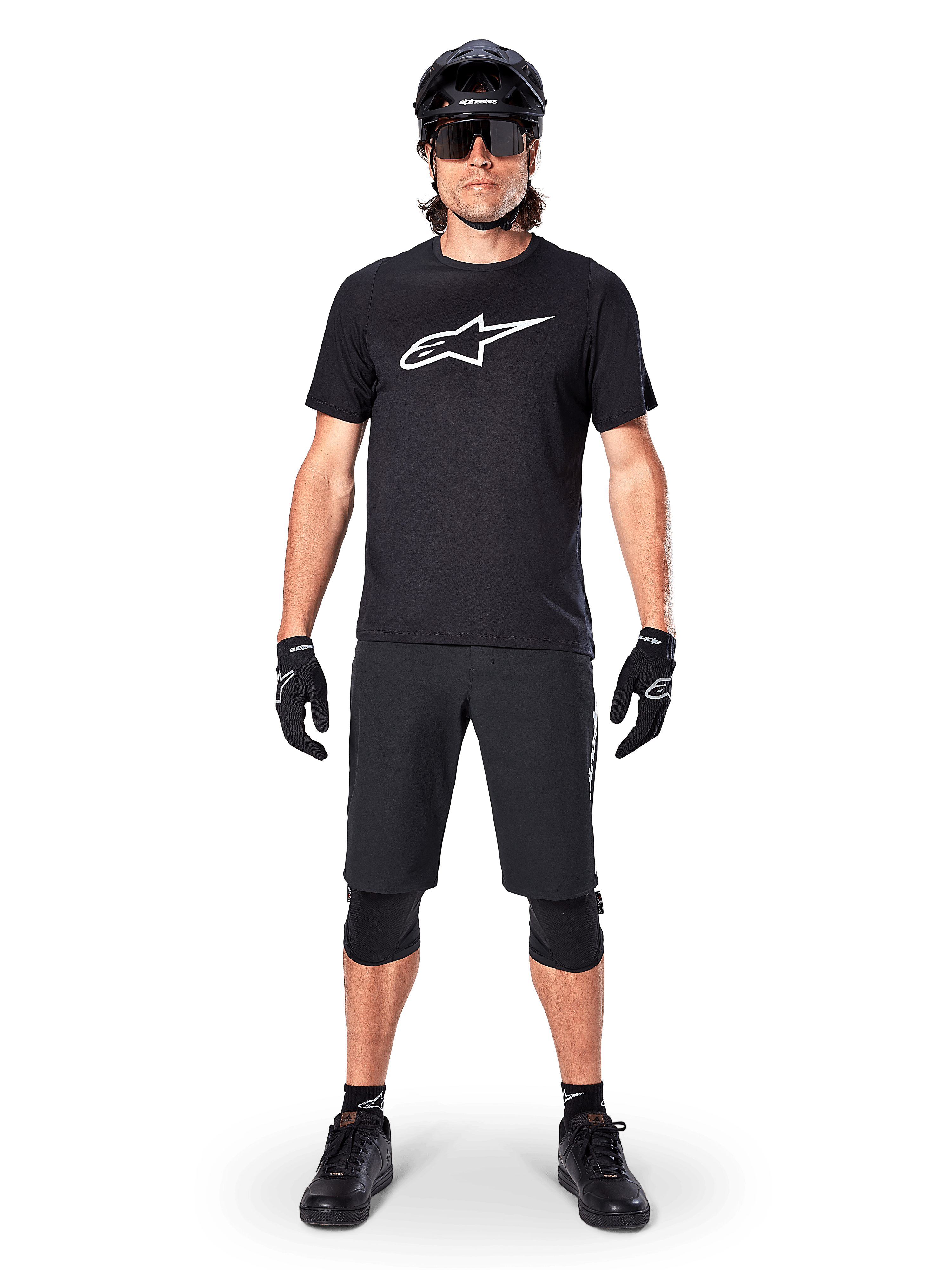 Jersey de manga corta Alpinestars A-Dura Dri Oscar, negro reflectante, combinado con pantalones cortos de MTB, guantes, rodilleras y casco negros a juego, con un gran logotipo de Alpinestars blanco en el pecho, equipamiento completo de ciclismo de montaña