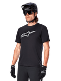 Alpinestars A-Dura Dri Oscar Jersey, camiseta de ciclismo MTB de manga corta, negra con logotipo blanco, tejido técnico transpirable, usada con casco negro, gafas de sol y guantes