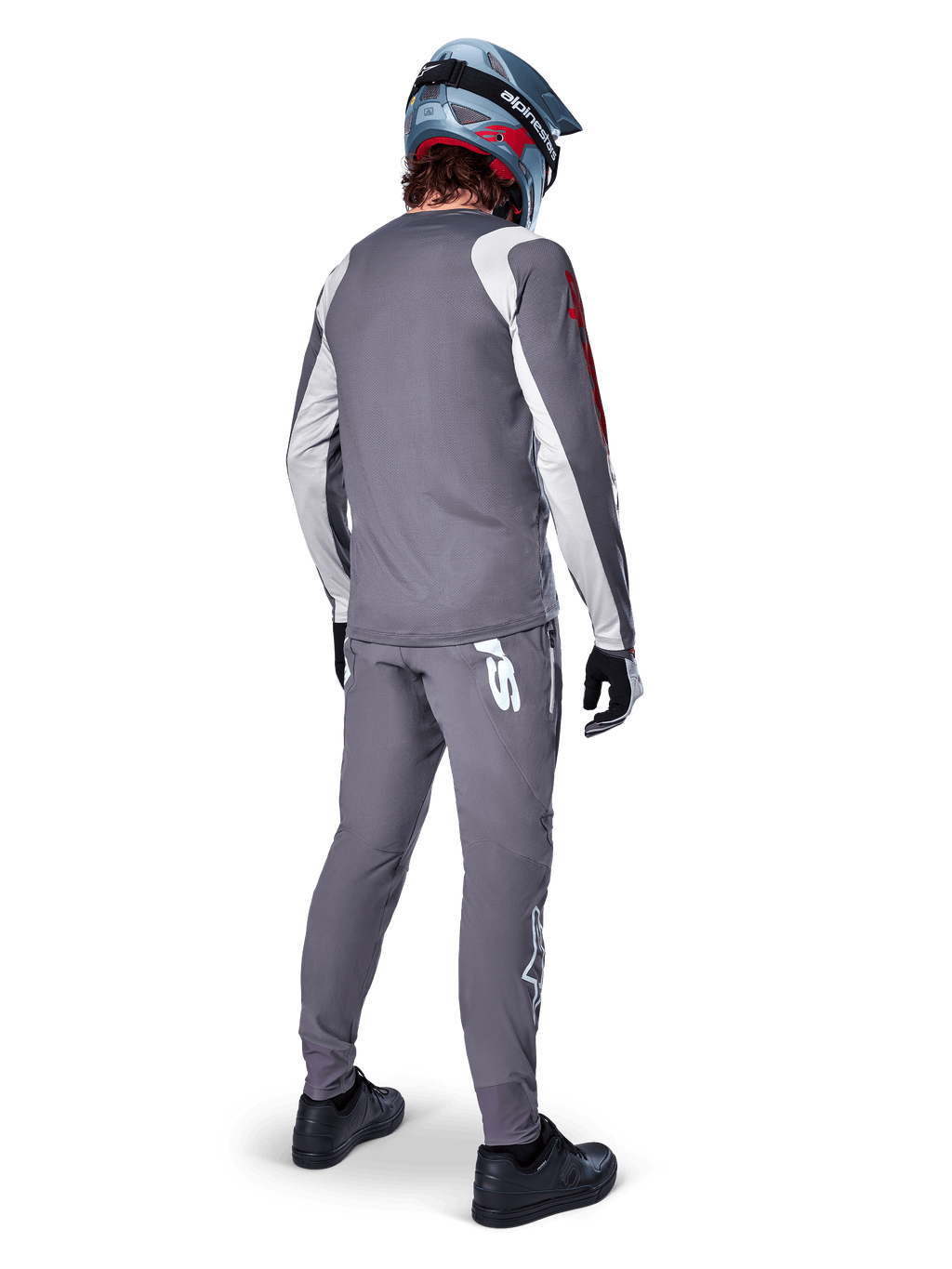 Alpinestars Jersey A-Supra Astar, jersey de MTB de manga larga, gris oscuro con detalles blancos en las mangas y logotipo rojo, vista trasera del ciclista con pantalones grises a juego y casco integral azul, ropa de ciclismo de alto rendimiento
