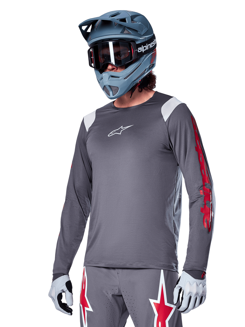Alpinestars A-Supra Astar Jersey de manga larga, jersey para ciclismo de montaña MTB, gris oscuro con detalles rojos y blancos, ajuste de rendimiento, usado con pantalones grises a juego con gráficos de estrellas rojas y blancas, equipo completo de ciclismo todoterreno con casco integral y guantes