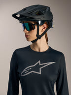 Jersey Stella A-Dura Ride de manga larga negro para mujer, con logotipo Astars gris y casco de MTB negro mate.