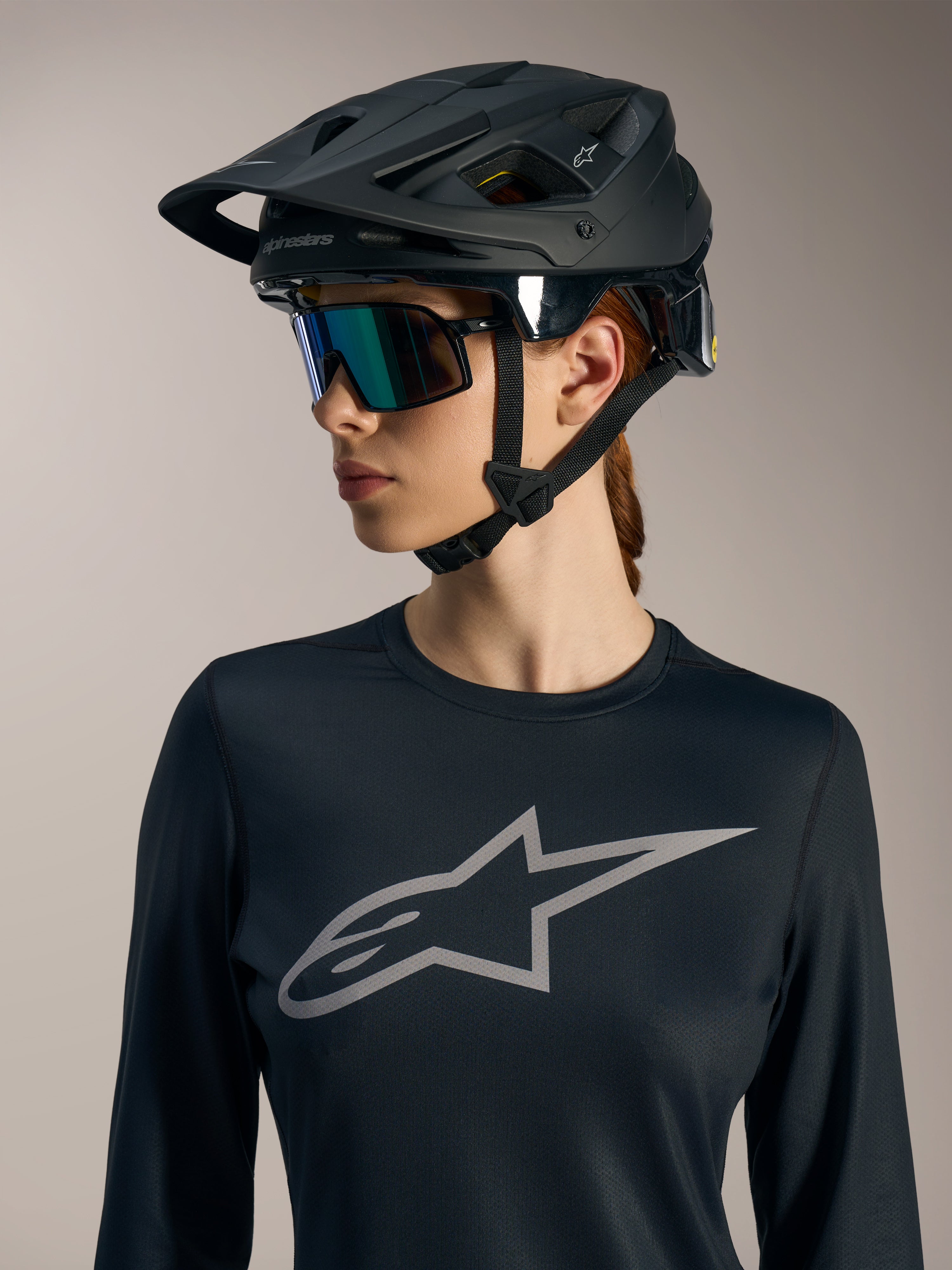 Jersey Stella A-Dura Ride de manga larga negro para mujer, con logotipo Astars gris y casco de MTB negro mate.