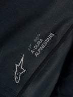 Primer plano del jersey Stella A-Dura Ride negro en tejido jacquard técnico con logotipos A-Dura Alpinestars y Astars.