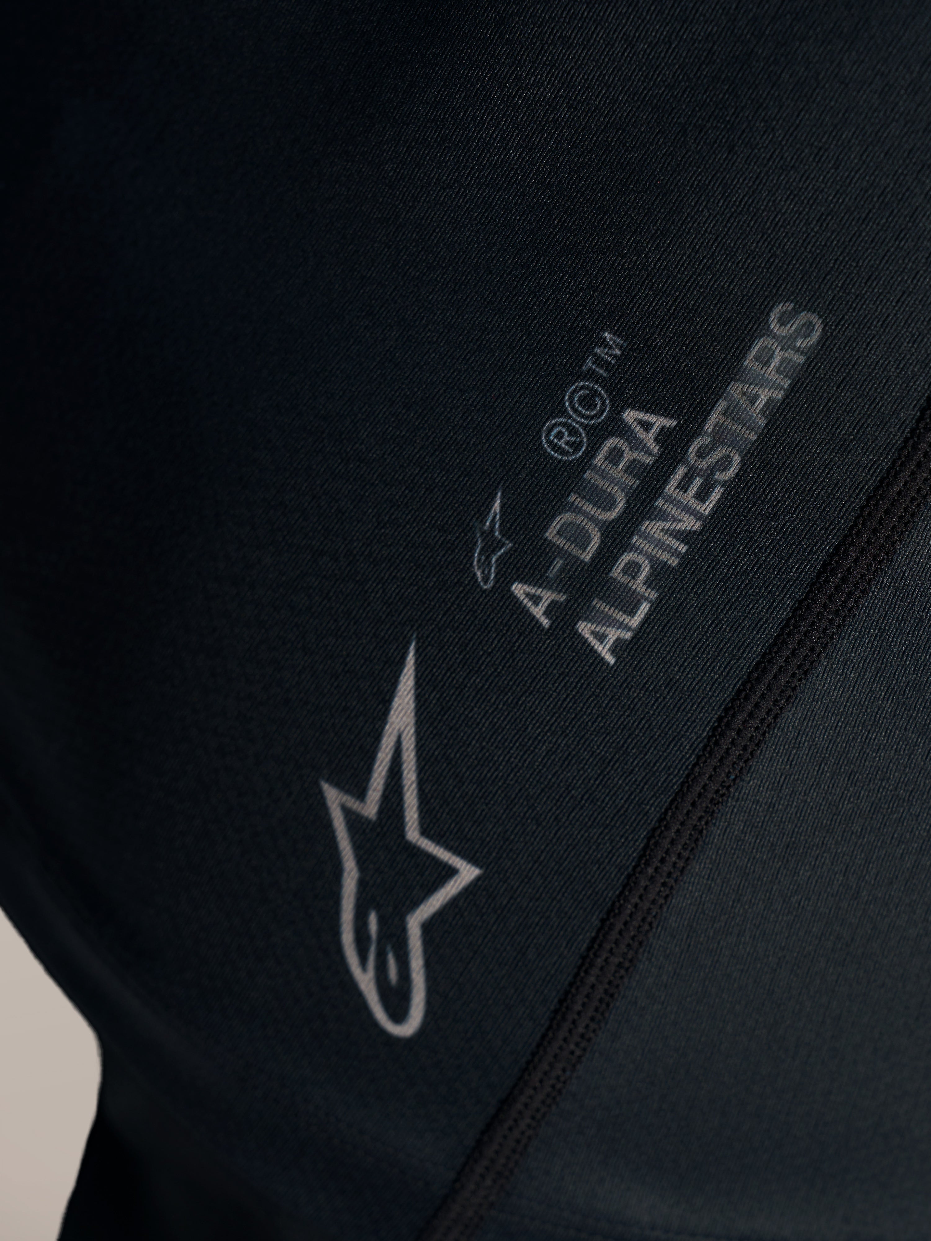 Detalle del jersey Stella A-Dura Ride negro con logotipo Alpinestars blanco y marca A-DURA en tejido jacquard.