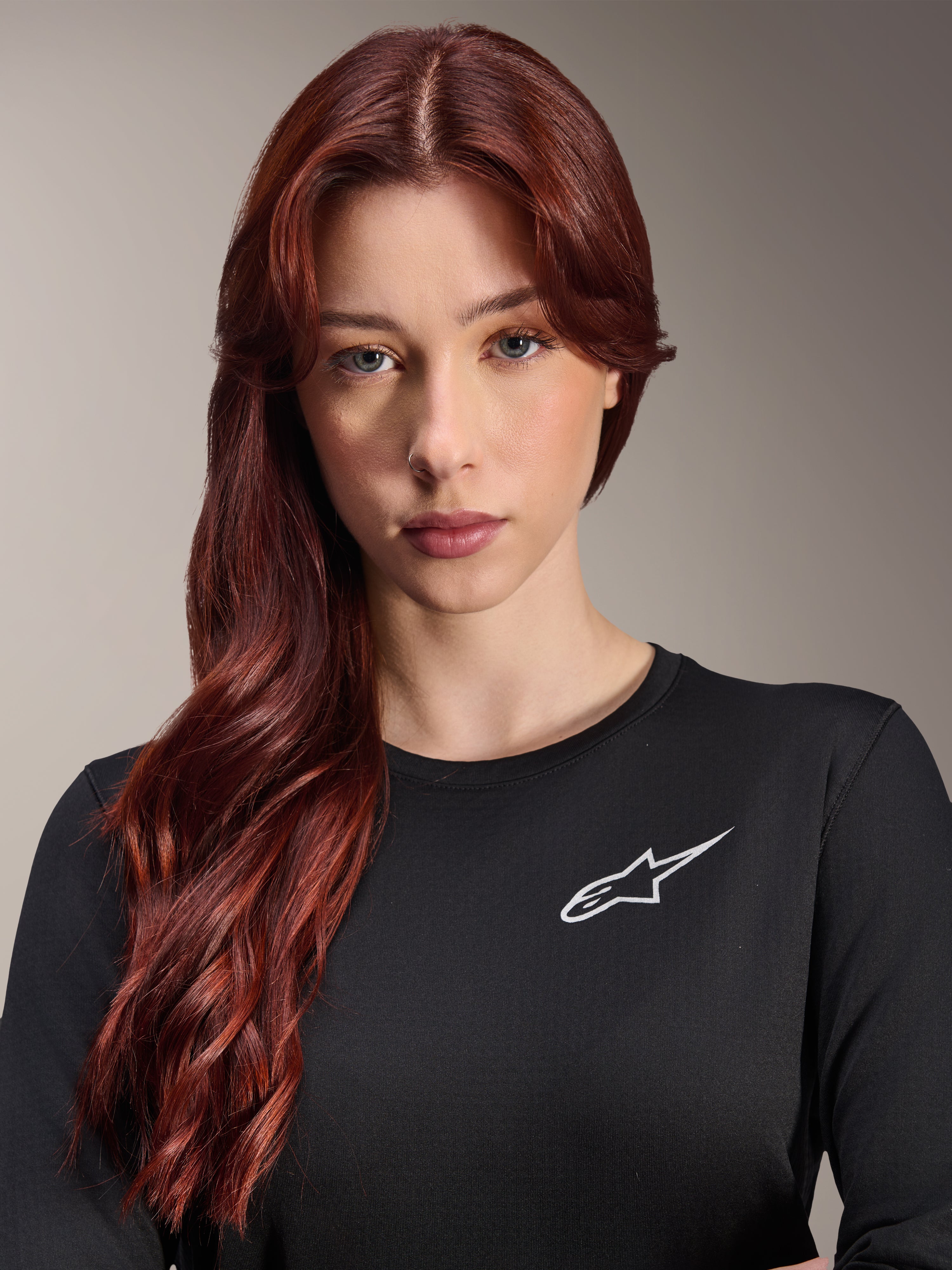 Alpinestars Stella A-Dura Thermal Jersey, jersey de MTB de manga larga para mujer, negro con el logotipo A-star blanco en el pecho, retrato de primer plano de una mujer con cabello largo y pelirrojo, ropa de ciclismo para climas fríos