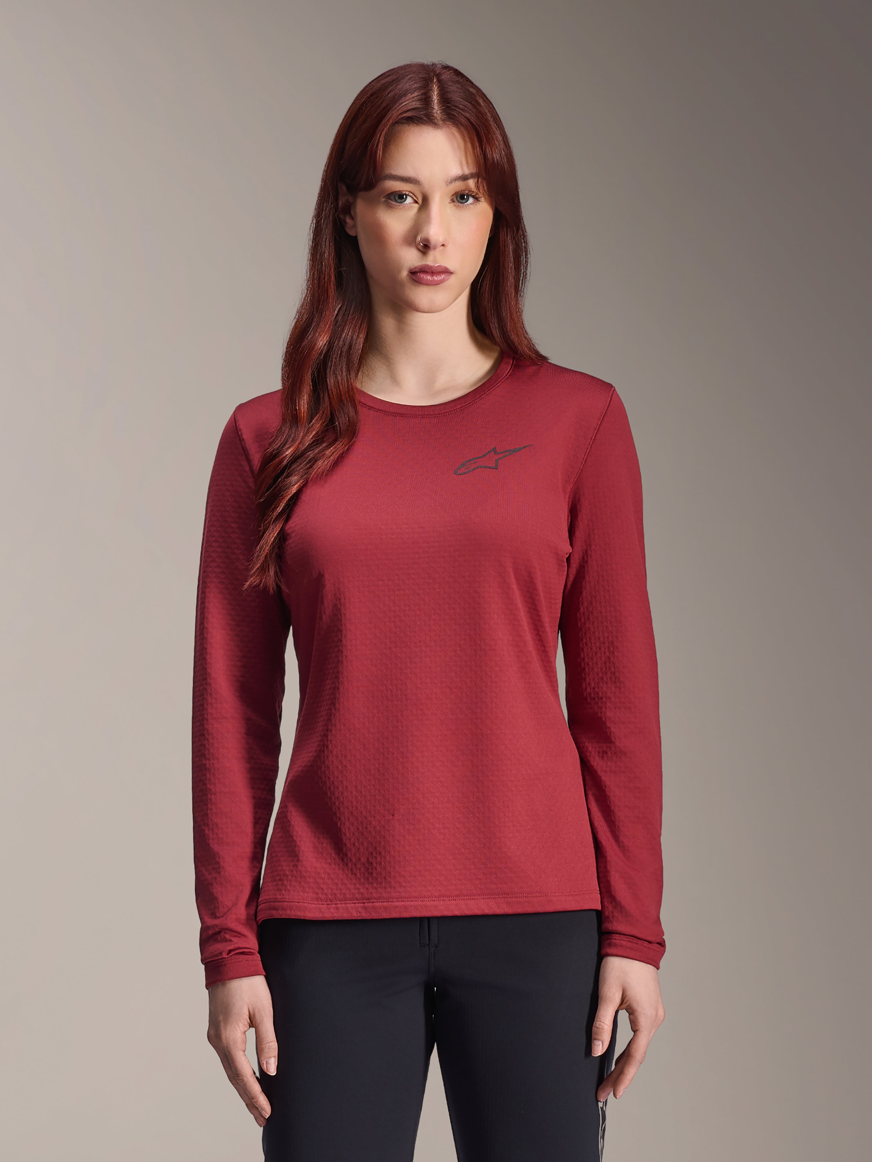 Alpinestars Stella A-Dura Thermal Jersey, jersey de MTB de manga larga para mujer, color granate, tejido térmico texturizado, cuello redondo con un pequeño logotipo de Alpinestars en color negro en el pecho, usado por una modelo.