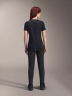Alpinestars Jersey Stella A-Dura Dri Switch de manga corta para mujer, negro, vista trasera en una modelo, con cola más larga y paneles de malla técnica, combinado con pantalones negros, equipamiento de alto rendimiento para ciclismo MTB