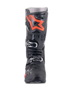 Botas Alpinestars Tech 10, botas de motocross, negro y rojo fluo, vista frontal, con un gran logotipo de estrella roja fluorescente en la placa de la espinilla, hebillas plateadas y un chasis de TPU negro duradero.