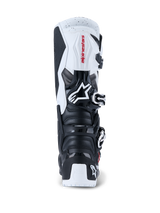 Botas Alpinestars 2026 Tech 7 Enduro, botas de motocross y enduro, negro y blanco, vista posterior que muestra las placas protectoras de TPU en el talón y la pantorrilla, logotipo de Alpinestars en rojo sobre el panel superior blanco y sistema de cierre con hebillas plateadas, diseñadas para conducción off-road de alto rendimiento