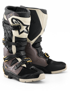 Botas Alpinestars 2026 Tech 7 Enduro Drystar®, botas de motocross y enduro, negro, gris oscuro y dorado, con una resistente carcasa de TPU, hebillas de aluminio de liberación rápida con detalles dorados y una placa de espinilla blanca grande con logotipo negro, diseñadas para durabilidad en terrenos todoterreno.