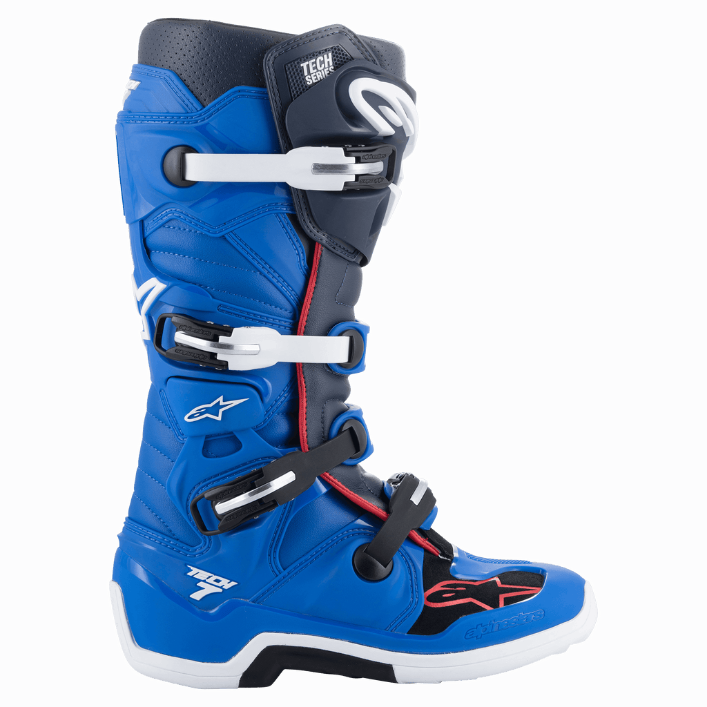 Botas Alpinestars Tech 7, botas de motocross en azul alpino, azul marino noche y rojo brillante, diseño de caña alta con sistema de cierre de cuatro hebillas blancas y negras, suela blanca con sección central negra y protección profesional para todoterreno.