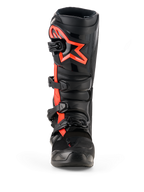 Botas Alpinestars Tech 7, botas de motocross, negro y rojo flúor, vista frontal, con un gran logotipo de estrella de Alpinestars en rojo flúor en la placa de la espinilla, sistema de cierre de cuatro hebillas y construcción duradera de TPU diseñada para carreras off-road.