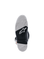 Vista de la suela de las botas Alpinestars Tech 7, botas de motocross, gris claro y negro, con una suela de caucho vulcanizado de doble compuesto, logotipo de Alpinestars en blanco, indicador de límite de desgaste rojo y patrón de agarre con textura de alta tracción.