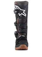 Botas Alpinestars Tech 7 Enduro, botas de motocross y enduro, negro y marrón oscuro, vista frontal que muestra el logotipo blanco en la espinillera, sistema de hebillas ajustables y suela de compuesto marrón resistente para agarre todoterreno.