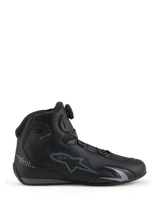 Zapatillas Alpinestars Celer, calzado para motociclismo, negro y gris oscuro, vista de perfil lateral mostrando el dial del Sistema de Cierre Rotor en la lengüeta, parte superior de microfibra técnica con el logo gris de Alpinestars, perfil aerodinámico deportivo y de competición