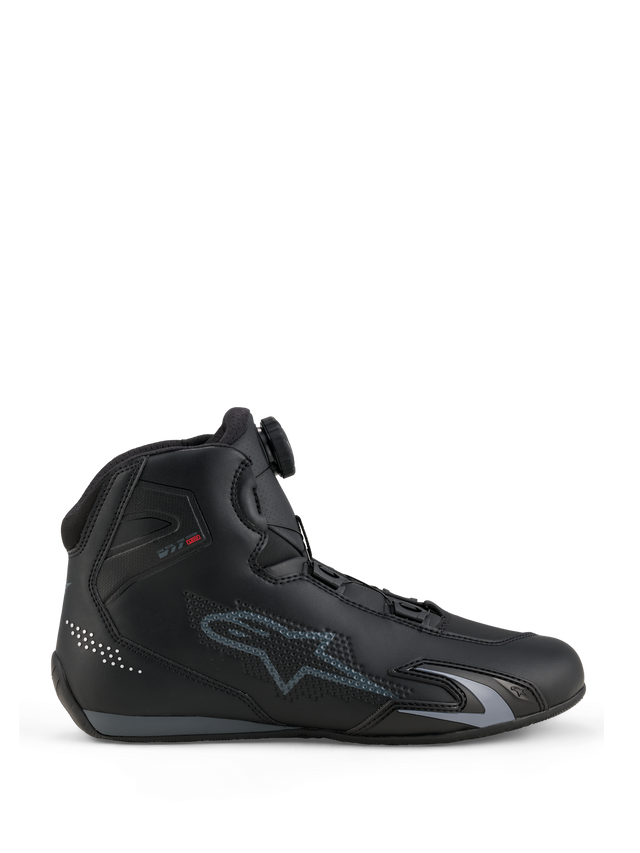 Zapatillas Alpinestars Celer, calzado para motociclismo, negro y gris oscuro, vista de perfil lateral mostrando el dial del Sistema de Cierre Rotor en la lengüeta, parte superior de microfibra técnica con el logo gris de Alpinestars, perfil aerodinámico deportivo y de competición