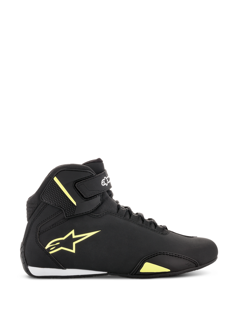 Zapatos Alpinestars Sektor, calzado para motociclismo, negro y amarillo fluorescente, vista lateral que muestra el logotipo de la estrella amarilla, correa en el tobillo con la marca y detalle blanco en el talón sobre una parte superior de microfibra elegante