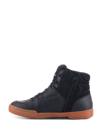 Zapatos Alpinestars Chrome Drystar®, Black Black Gum, calzado urbano para motociclismo con parte superior de cuero y gamuza negra, perfil de zapatilla de caña alta, suela de goma de color caramelo y cierre de cremallera lateral.