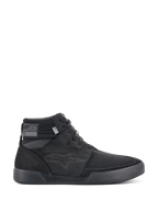 Alpinestars Primer Riding Shoes, zapatillas de moto negras, calzado urbano de caña alta, vista de perfil, parte superior de malla texturizada, suela de goma gruesa, diseño deportivo moderno con un sutil logo de estrella