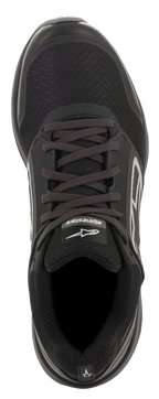 Zapatos Alpinestars Meta Trail, negro y gris oscuro, vista superior, parte superior de malla negra con cordones, logotipo blanco de Alpinestars en la lengüeta, calzado de alto rendimiento para paddock e inspirado en el running