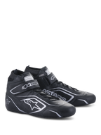 Alpinestars Tech-1 T V3 Shoes FIA, zapatos de automovilismo, negro y plata, confección en cuero de vaca con logotipos y marca Alpinestars en plata, vista lateral en ángulo con correa de gancho y bucle y cierre de cordones