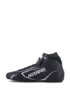 Zapatos Alpinestars Tech-1 T V3 FIA, calzado de automovilismo, negro y plata, vista de perfil lateral, construcción de cuero de vaca completo con marca ASTARS plateada, correa de gancho y bucle ajustable y cuello elástico ignífugo.