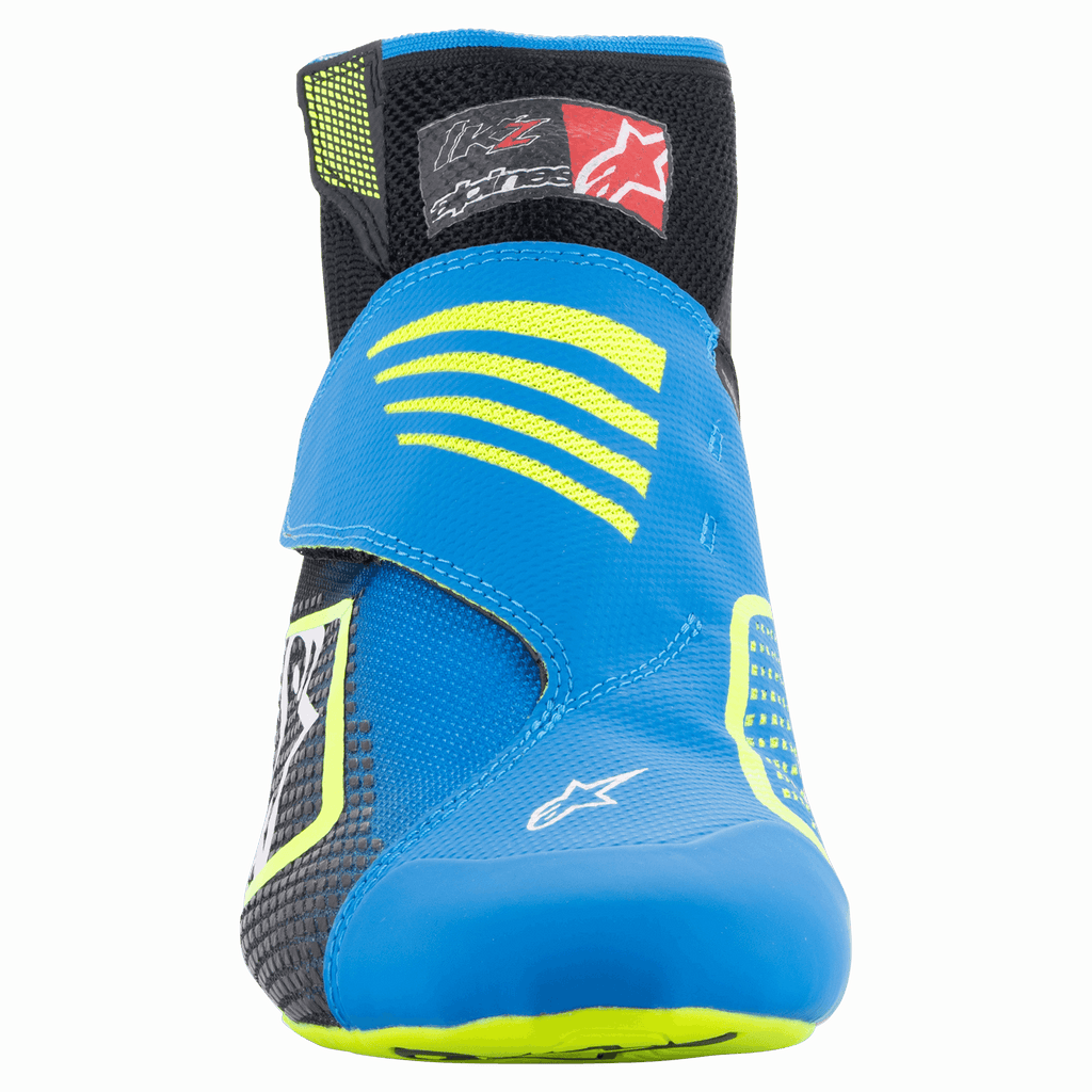 Zapatos Alpinestars Tech-1 KZ V2, zapatos de karting, negro, azul esmalte y amarillo flúor, vista frontal que muestra la parte superior de punto sin costuras, correa azul vibrante con detalles en amarillo y cuello del tobillo en negro.