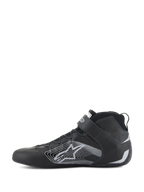 Alpinestars Tech-1 Z V3 Shoes FIA, zapatos de automovilismo en negro y plata, vista de perfil lateral, parte superior de cuero bovino premium con un gran logotipo de estrella estilizada en plata, correa de velcro en el tobillo y diseño elegante de caña alta para rendimiento profesional en deportes de motor