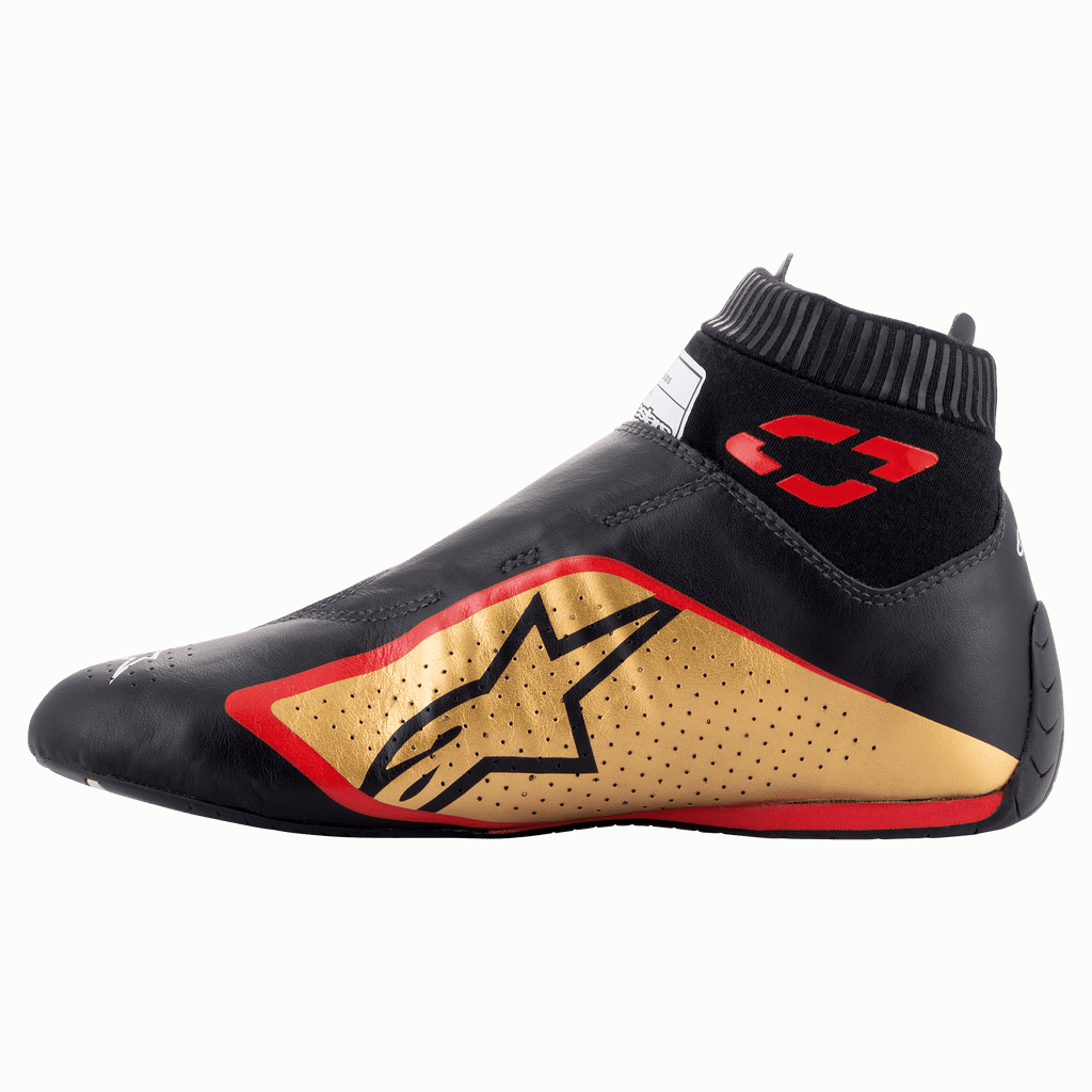 Zapatos Alpinestars Supermono V2 FIA, calzado para automovilismo, negro, dorado y rojo, vista de perfil lateral con una elegante construcción de cuero de una sola pieza, panel lateral dorado con logo de estrella negra, detalles en rojo y cuello elástico acanalado.