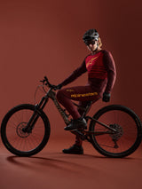 Conjunto bordeaux A-Dura Elite 2.0 de Alpinestars, ciclista de montaña con bicicleta Specialized en estudio.