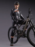 Jersey Alpinestars A-Dura Ride Camo de manga larga negro con logo naranja, ciclista de montaña en estudio.