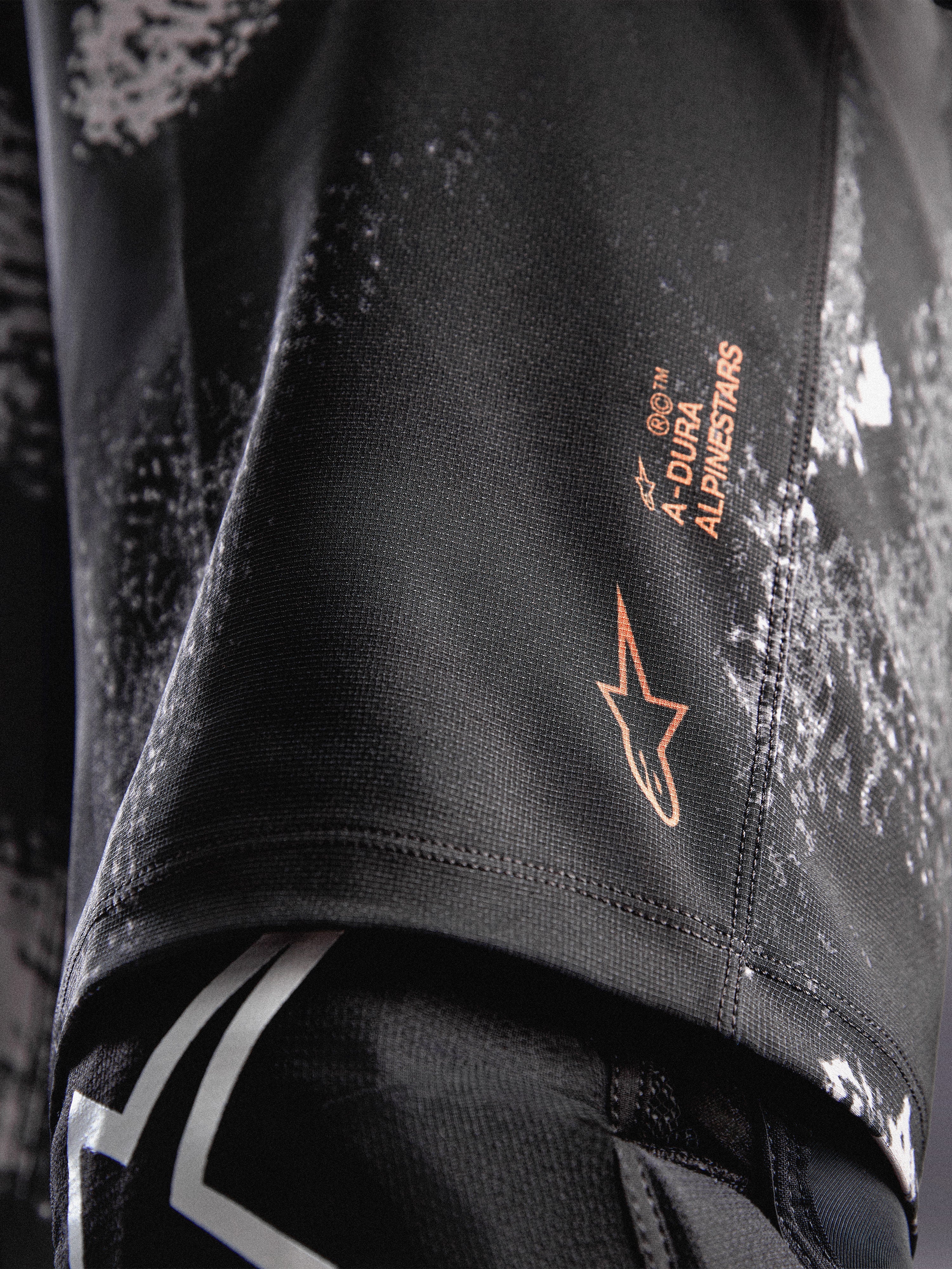 Pantalones cortos A-Dura Ride en camuflaje negro con logotipo naranja Alpinestars y tejido elástico duradero para MTB.