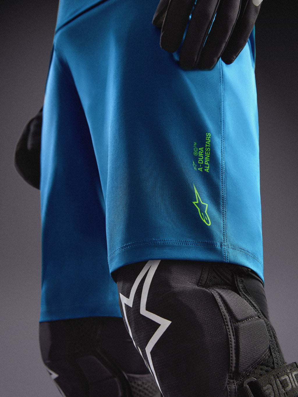 Pantalones cortos Alpinestars A-Dura Ride azul verdoso con logos verde lima, combinados con rodilleras para MTB