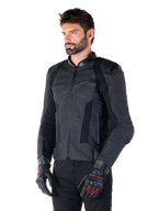 Piloto usando la chaqueta de cuero Alpinestars Missile V3 en negro, de cuero bovino premium con paneles perforados en el pecho y protectores externos DFS en los hombros, combinada con pantalones negros y guantes de carreras en negro y rojo.