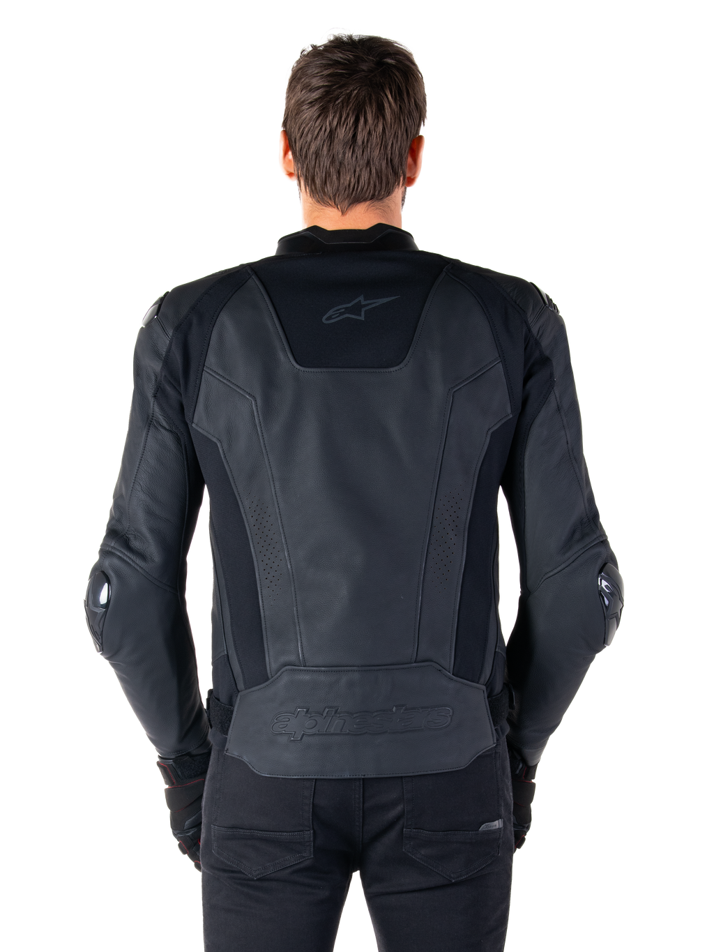 Vista trasera de un piloto con la chaqueta de cuero Alpinestars Missile V3 en color negro, destacando su construcción en cuero premium con paneles elásticos técnicos, logotipo de Alpinestars en relieve en la parte inferior de la espalda y marca sutil en la parte superior, combinada con pantalones negros para un look deportivo de competición.