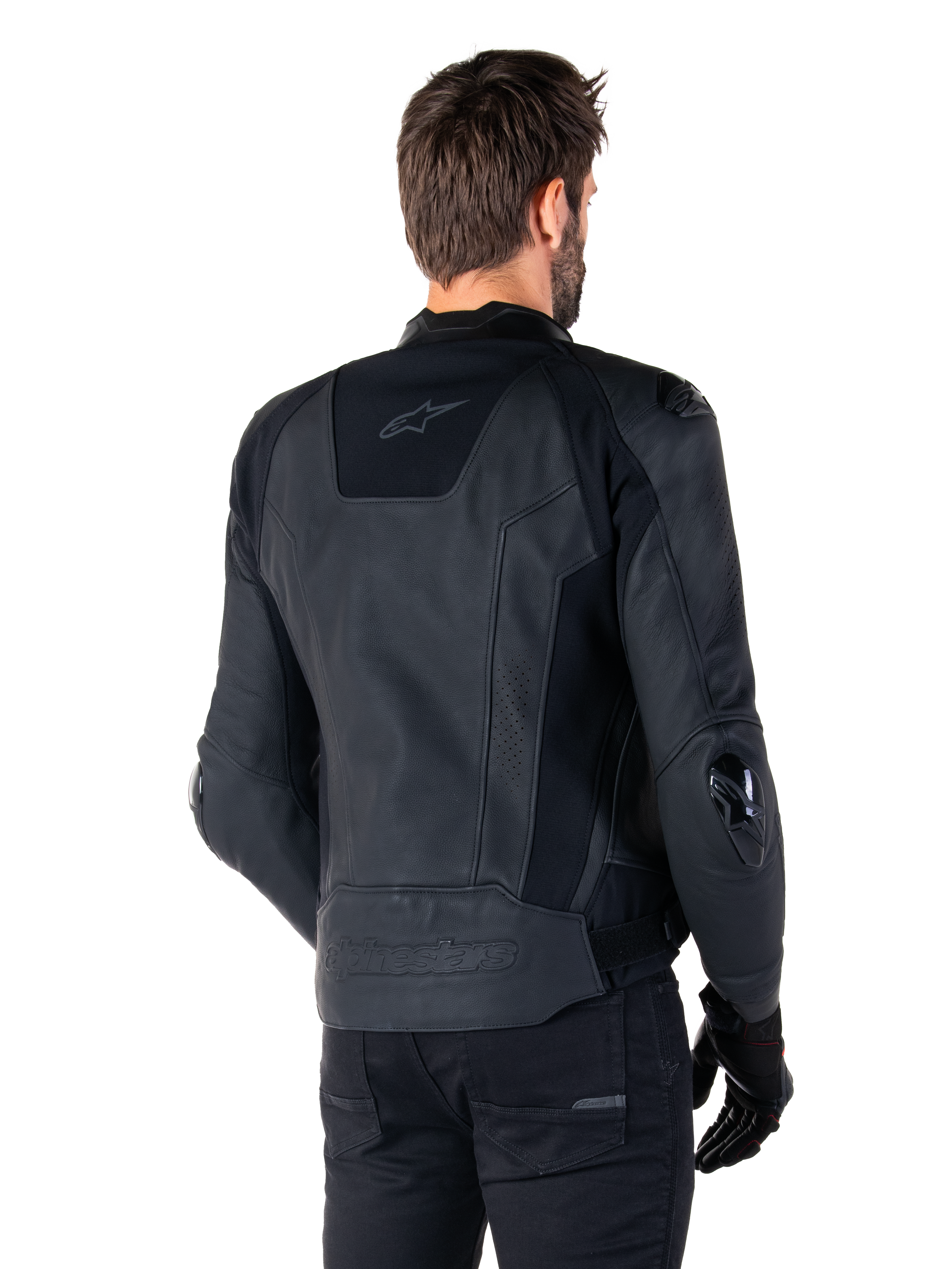 Alpinestars Missile V3 Leather Jacket, chaqueta de cuero negra, vista trasera en modelo, chaqueta deportiva de competición premium con confección en cuero, con la marca Alpinestars en relieve en la parte inferior de la espalda y deslizadores de codo de TPU.