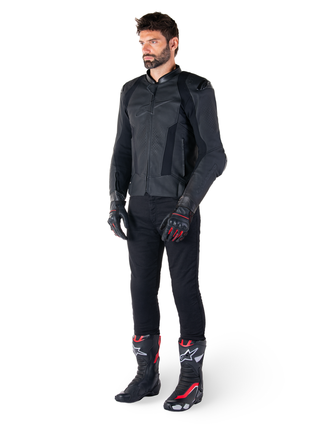 Chaqueta de cuero Alpinestars Missile V3, negra, usada por un piloto con pantalones negros y guantes y botas de carreras en negro y rojo, con paneles de cuero perforado y logotipos monocromáticos elegantes, estética deportiva de competición profesional