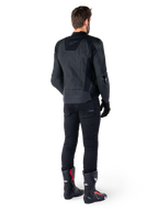 Chaqueta de cuero Alpinestars Missile V3 en color negro, vista trasera en un piloto, combinada con pantalones negros y botas de competición negras y rojas, con una elegante confección en cuero, logotipos en el mismo tono y un ajuste de alto rendimiento para competición