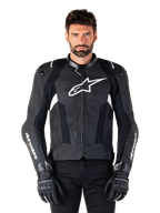 Chaqueta de cuero Alpinestars Missile V3, negra con logotipos blancos, usada por un modelo con guantes de conducción negros, chaqueta de carreras de motociclismo de cuero premium con paneles de ventilación perforados y características de alto rendimiento