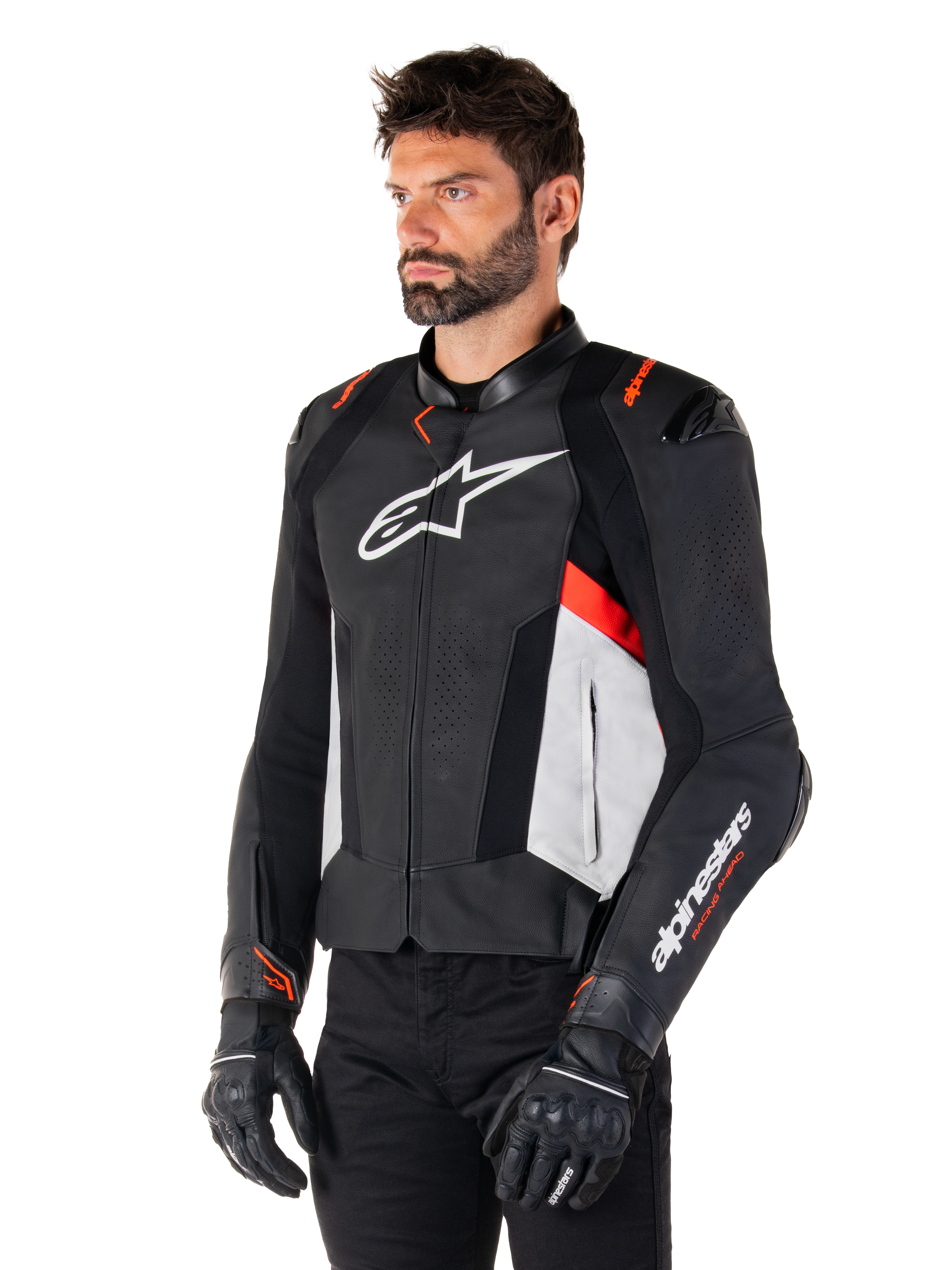 Chaqueta de cuero Alpinestars Missile V3, negro, blanco y rojo flúor, chaqueta de moto deportiva de competición usada por un modelo con guantes y pantalones negros, con paneles de cuero perforado y logotipos de Alpinestars destacados