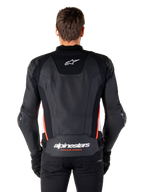 Chaqueta de cuero Alpinestars Missile V3, vista trasera, cuero negro premium con detalles en rojo flúor y blanco, con el logotipo de la estrella blanca en la parte superior de la espalda y la marca Alpinestars en la parte inferior de la espalda, usada con pantalones y guantes negros.