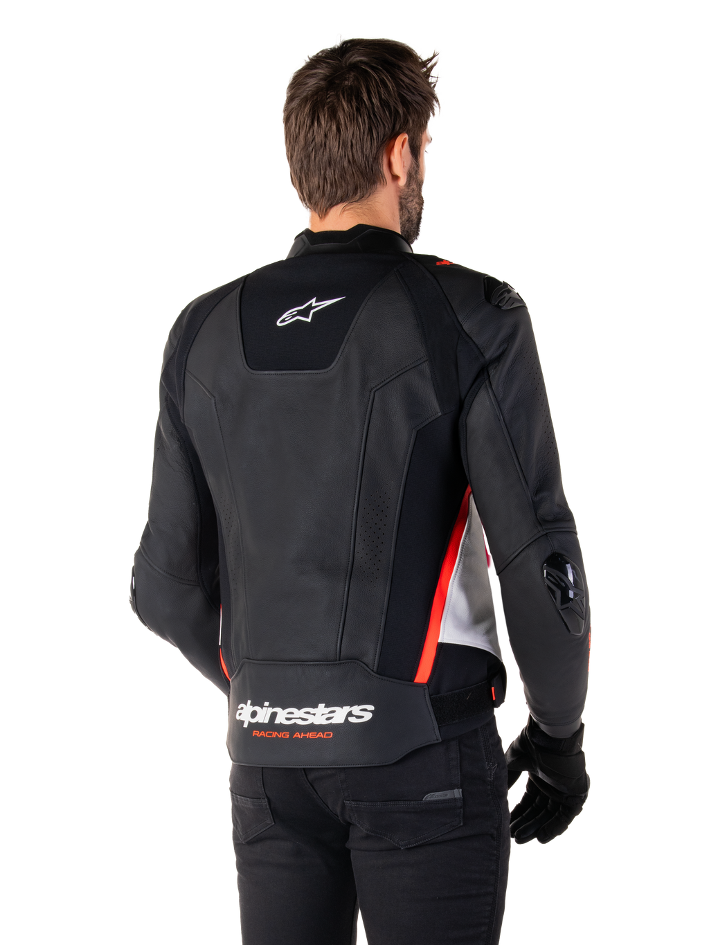 Chaqueta de cuero Alpinestars Missile V3, vista posterior en un piloto, Negro, Blanco y Rojo Flúor, con el distintivo logotipo de Alpinestars y el texto 'RACING AHEAD' en la parte inferior de la espalda, confección en cuero premium con paneles elásticos técnicos y deslizadores protectores de TPU, usada con guantes y pantalones negros.