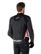 Chaqueta de cuero Alpinestars Missile V3, vista posterior en un piloto, Negro, Blanco y Rojo Flúor, con el distintivo logotipo de Alpinestars y el texto 'RACING AHEAD' en la parte inferior de la espalda, confección en cuero premium con paneles elásticos técnicos y deslizadores protectores de TPU, usada con guantes y pantalones negros.