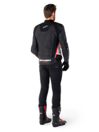 Chaqueta de cuero Alpinestars Missile V3 en Negro Blanco Rojo Fluo, vista trasera en un piloto masculino, con logotipos de Alpinestars en la parte superior e inferior de la espalda, combinada con pantalones negros y botas de moto, chaqueta deportiva de cuero inspirada en la competición