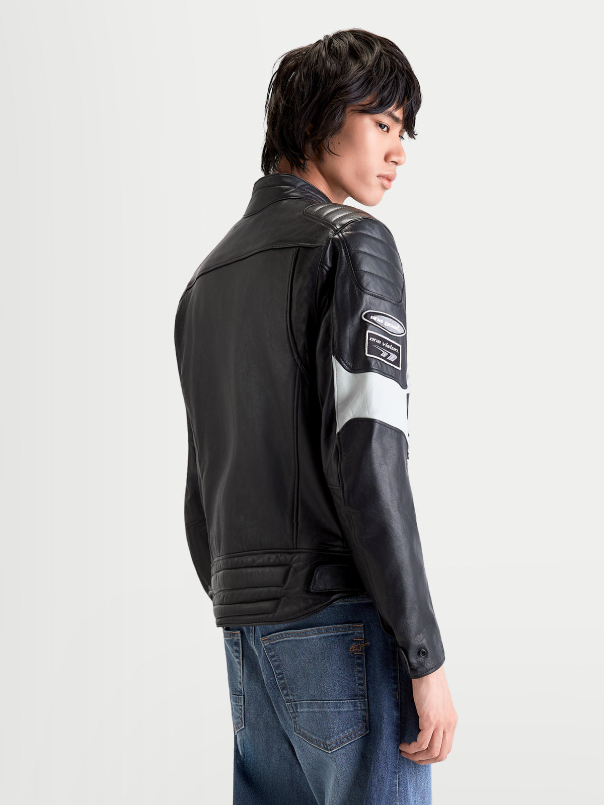 Alpinestars Revern Leather Jacket, men's urban motorcycle leather jacket in black and metal gray, back profile view on a model wearing distressed full-grain bovine leather with racing-derived branding and armor-ready construction