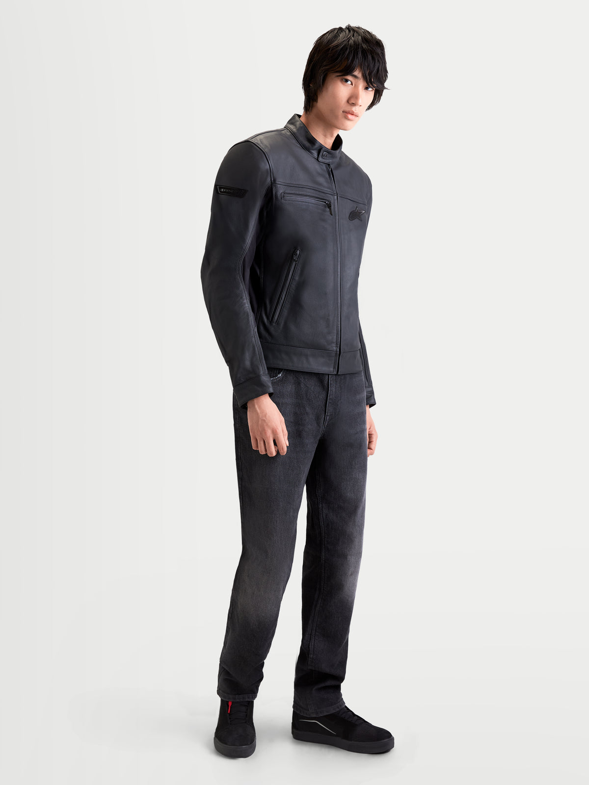 Alpinestars Maver X Chaqueta de cuero, chaqueta de moto urbana contemporánea para hombre en color negro, vista de perfil lateral usando un modelo que muestra la construcción en cuero bovino y cuello de estilo motero