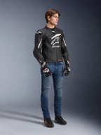 Alpinestars GP Plus R V4 Rideknit Leather Jacket, negro y blanco, chaqueta de cuero para moto vestida por un modelo con vaqueros azules y guantes negros, con un prominente logotipo blanco de Astars en el pecho, paneles perforados y detalles blancos en los hombros.
