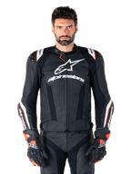 Chaqueta de cuero Alpinestars Missile V3 Ignition, negra con detalles en blanco y rojo, lucida por un modelo masculino con guantes y pantalones de carreras a juego, chaqueta deportiva de motociclismo derivada de MotoGP con logotipos llamativos